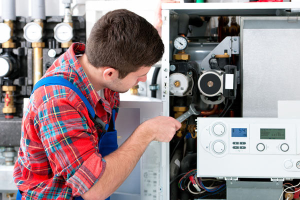 HVAC technician inspecting and repairing boiler controls in Sun City
