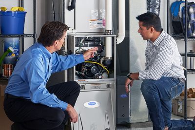 65df8c11f3e4c468cbd351a5_furnace repair vs replacement – Copy HVAC technician explaining furnace repair and maintenance to a homeowner in Sun City, AZ